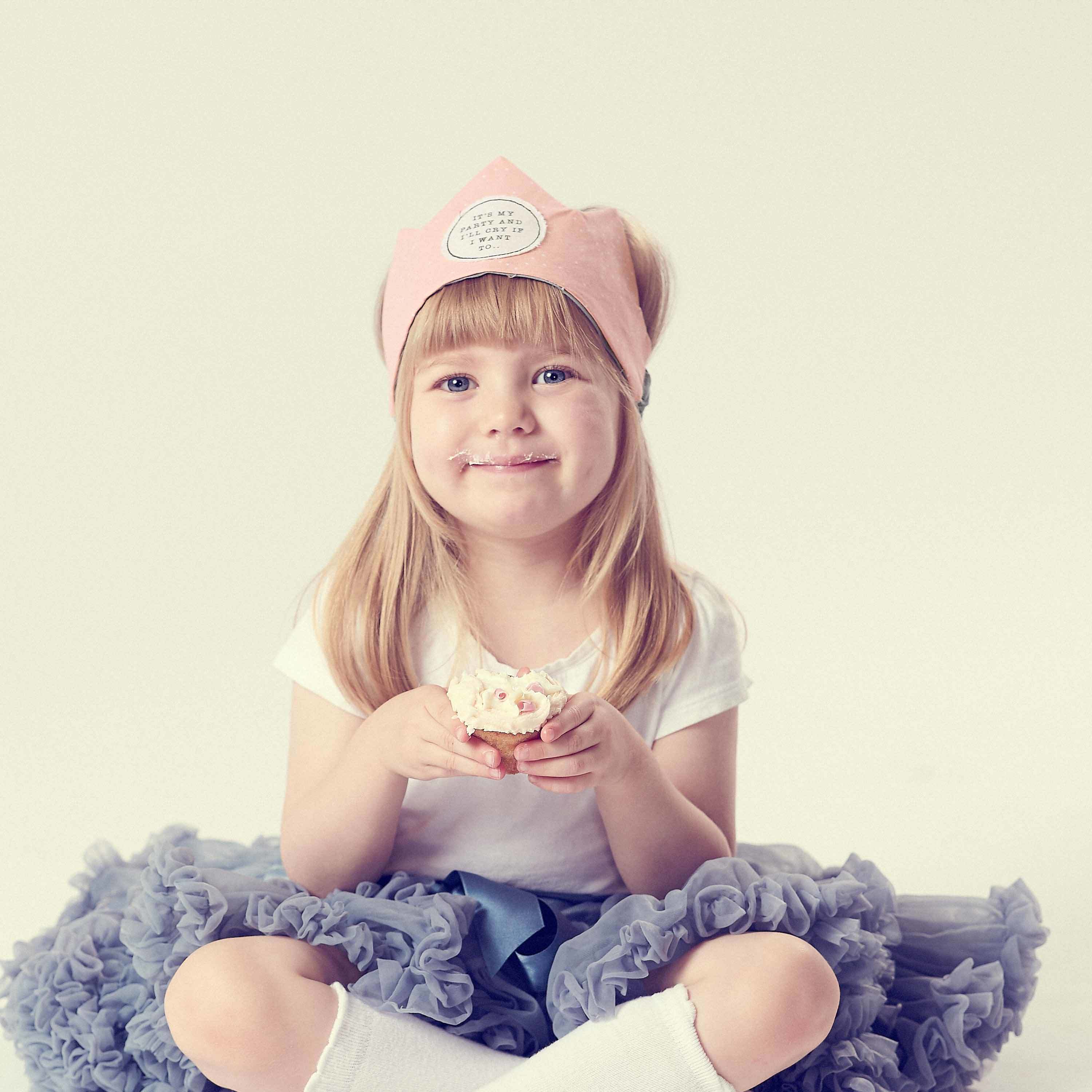 children's accessories, girl wearing tutu and crown eating a cake