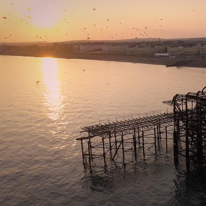 Brighton West Pier at sunset with views of the coastline taken on drone