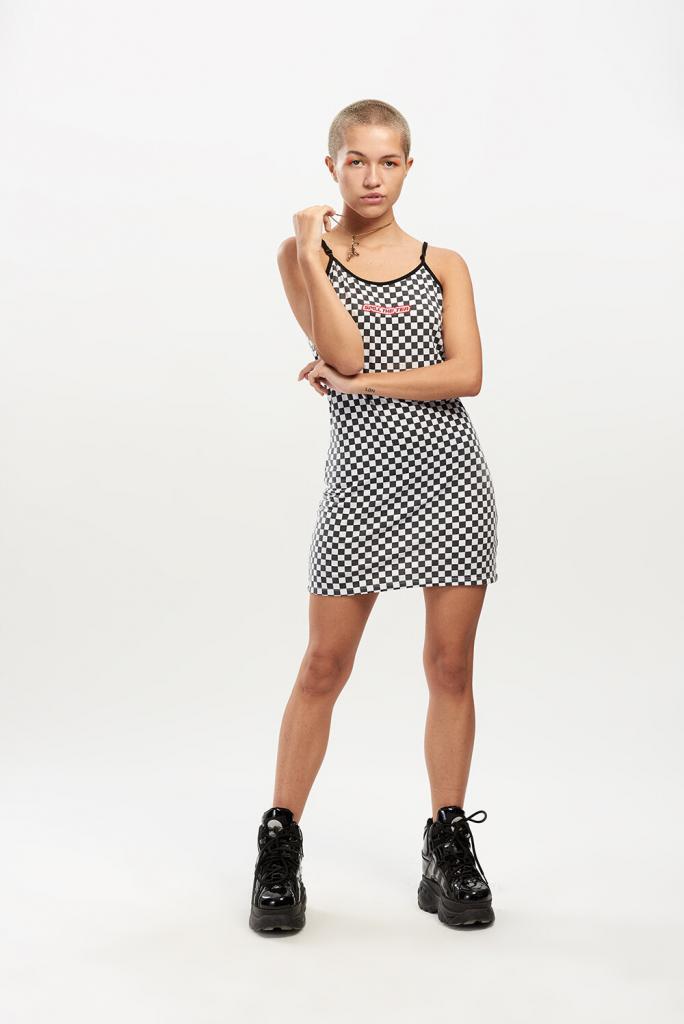 90s style on-trend fashion photoshoot, worn by a female model wearing a black and white checkered mini dress with black chunky platforms